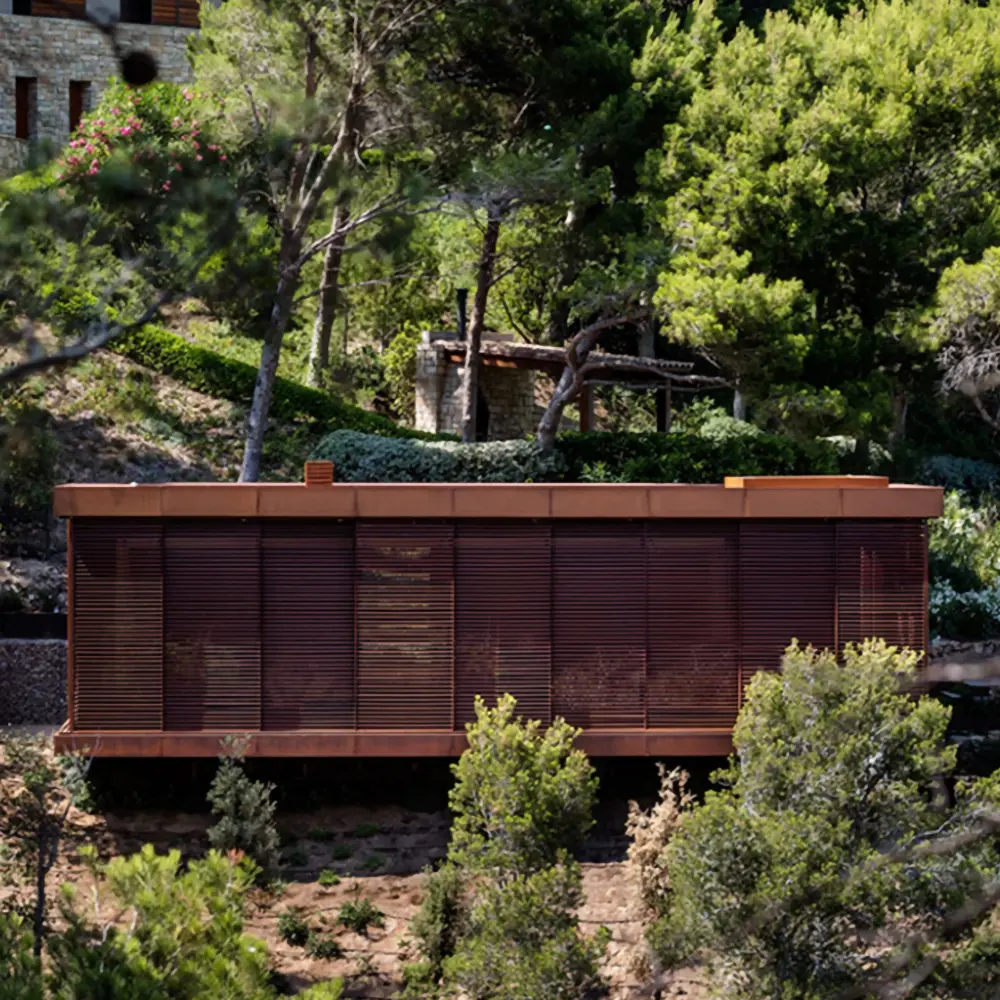 Pabellón de invitados de acero corten en medio del bosque